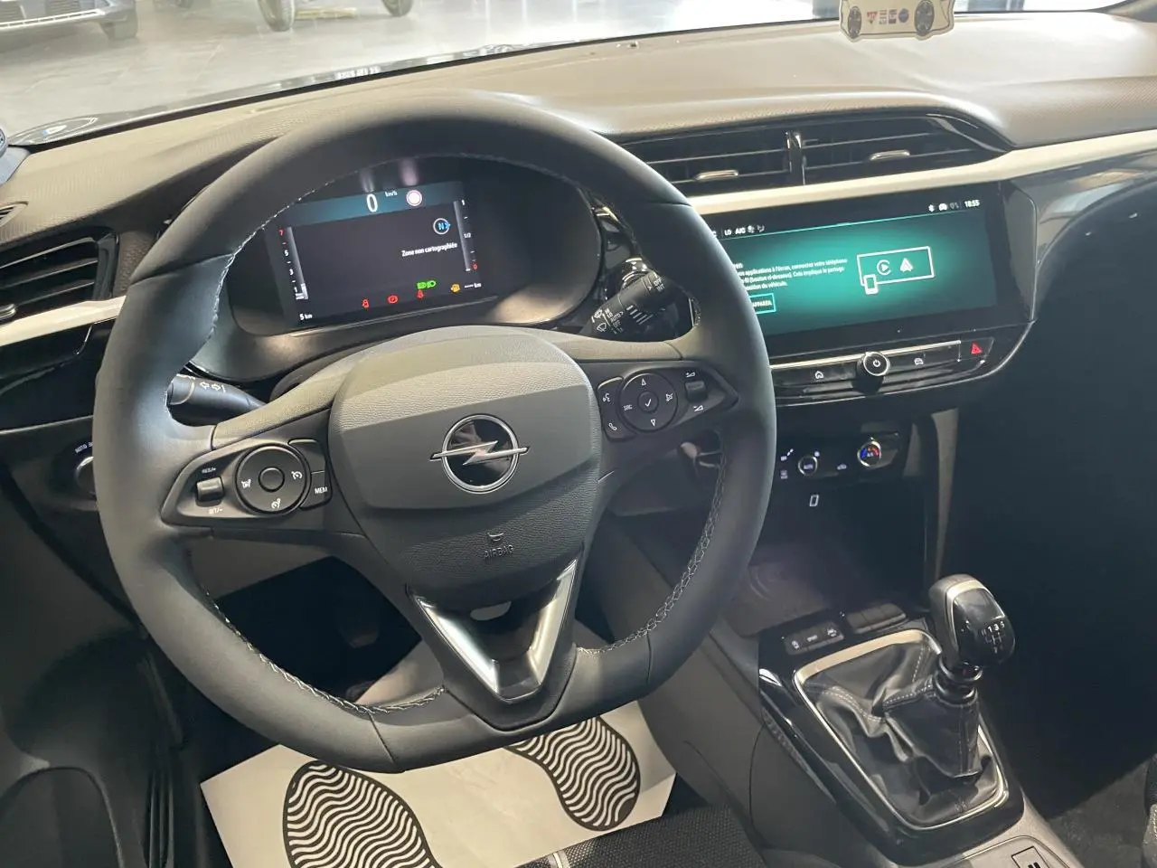 Vue intérieure centrée sur le volant noir et la console centrale avec levier de vitesse manuelle de l'Opel Corsa gris.