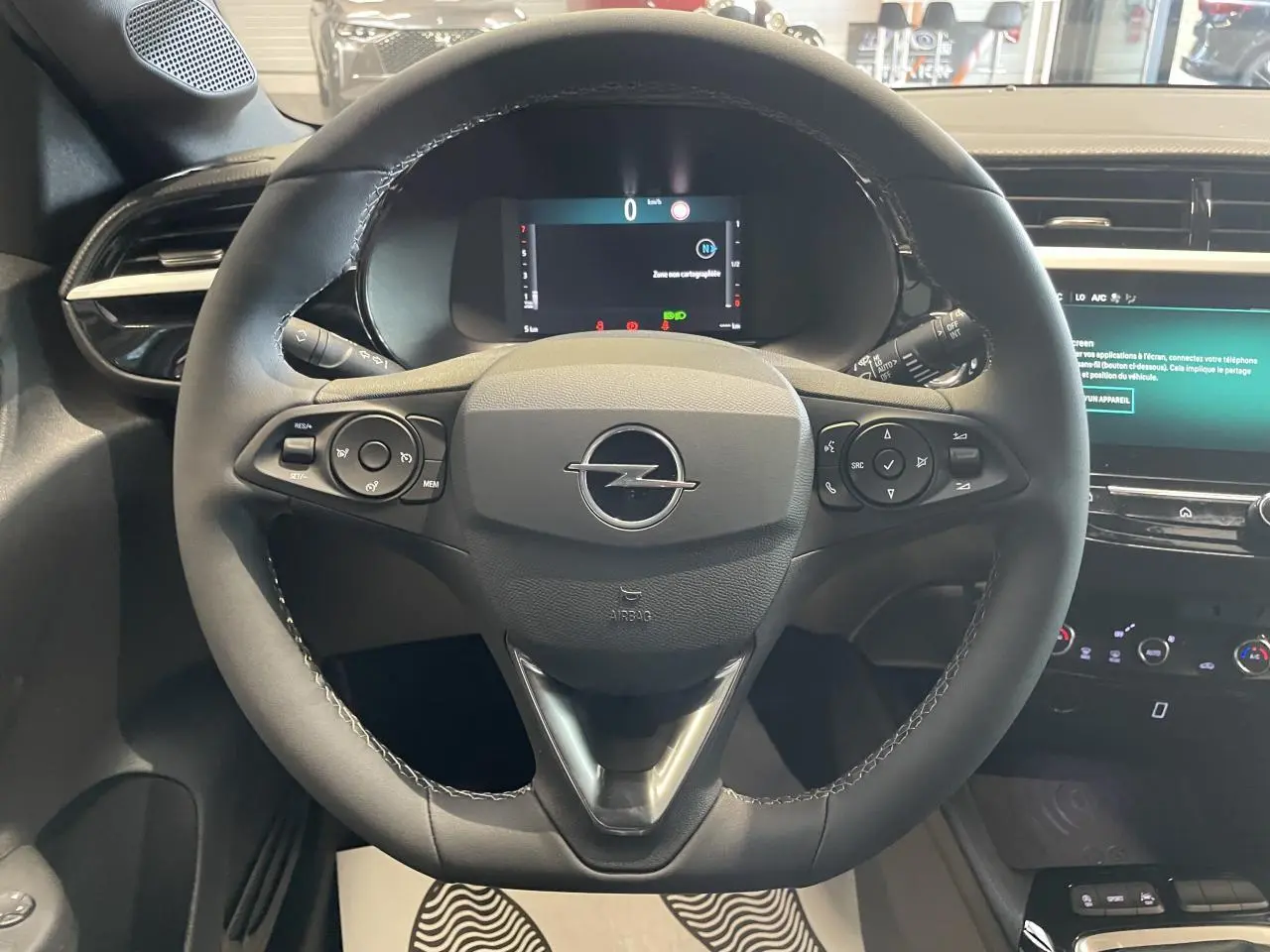 Vue rapprochée du volant noir en cuir synthétique d'une Opel Corsa 2026 avec tableau de bord numérique et écran tactile.