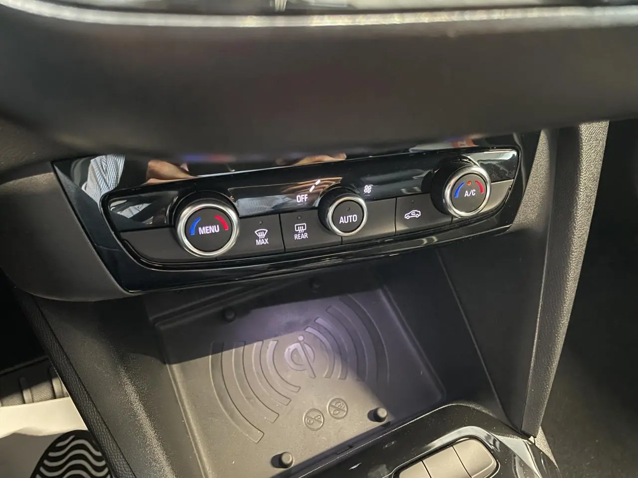 Gros plan sur la console centrale de l'Opel Corsa gris, montrant la commande de climatisation et le chargeur sans fil.