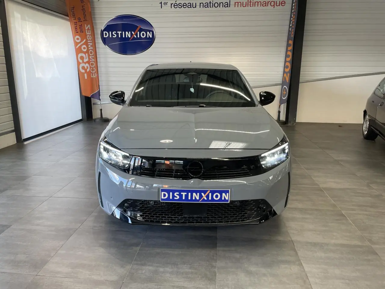 Vue frontale d'une Opel Corsa gris Grafik avec calandre noire et phares LED allumés en showroom.
