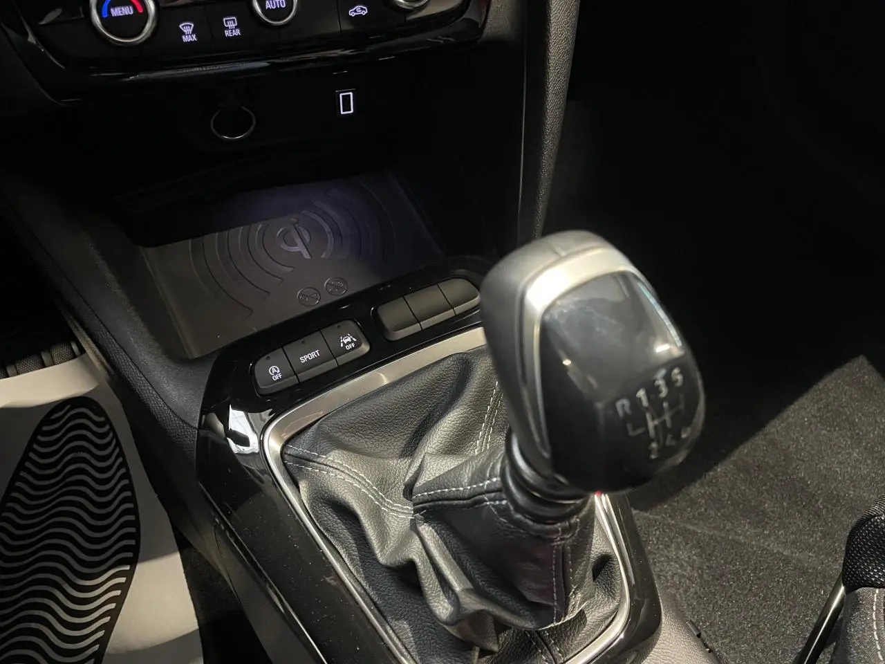 Gros plan sur la commande de la boîte manuelle noire et le chargeur à induction dans l’habitacle de l’Opel Corsa gris.