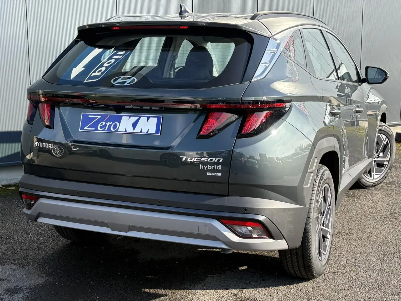 Vue 3/4 arrière droite du Hyundai Tucson Cypress Green avec feux arrière LED et logo hybride visible.