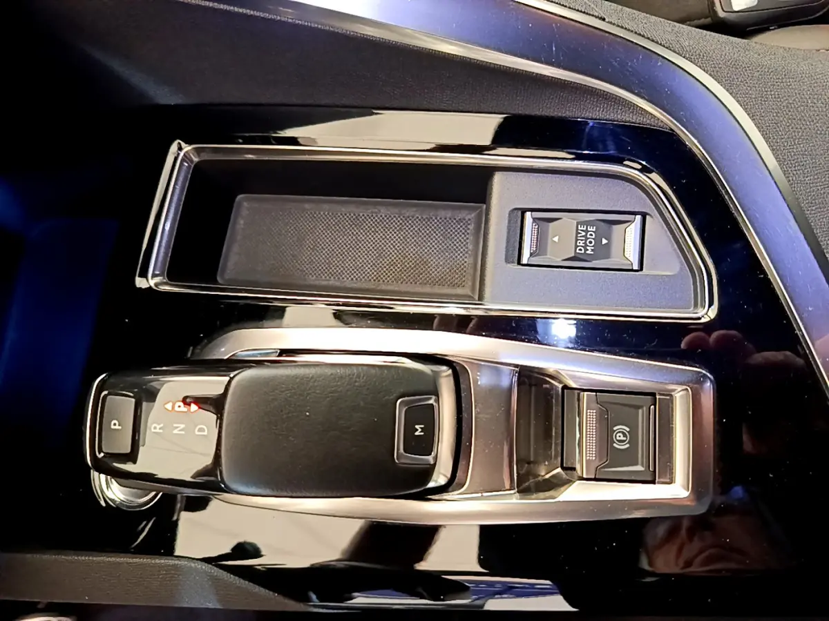 Gros plan sur la console centrale noire brillante du Peugeot 5008 2021 avec levier de boîte auto et boutons Drive Mode et frein électrique.