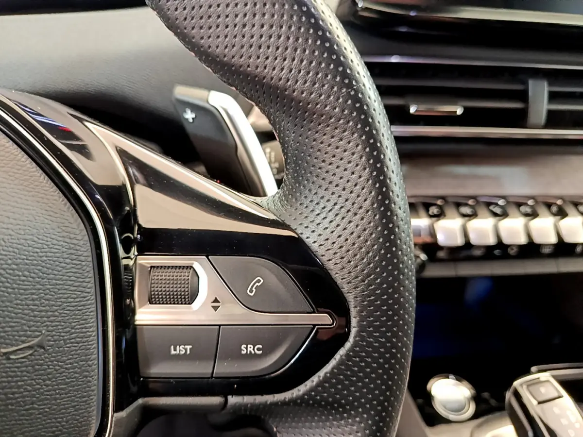 Gros plan sur la partie gauche du volant perforé noir du Peugeot 5008 GT Pack 2021, avec commandes intégrées.
