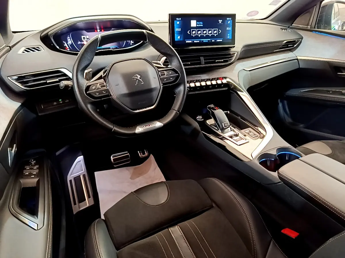 Vue intérieure avant du Peugeot 5008 GT Pack 2021, volant compact, écran tactile central et sellerie noire élégante.