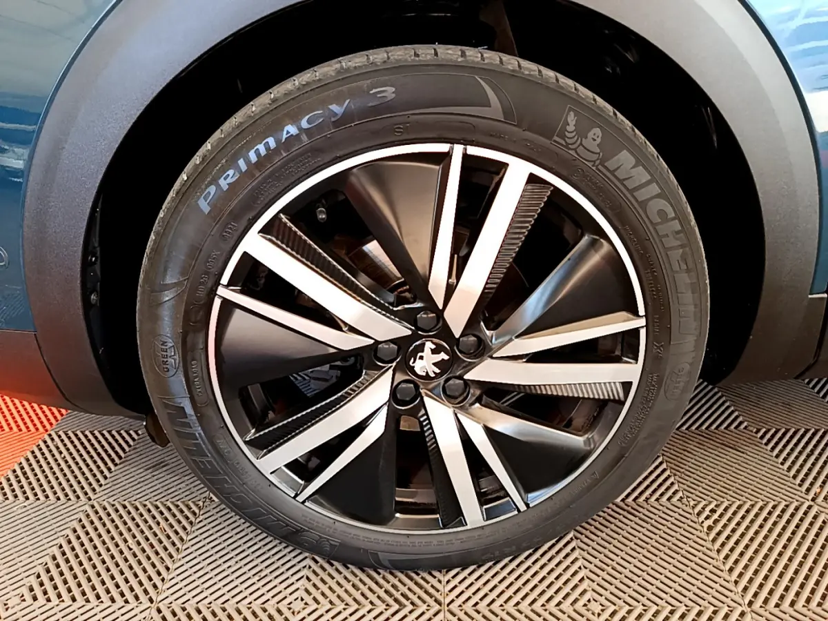 Gros plan sur la roue avant droite bleu d'un Peugeot 5008 GT Pack avec jante alliage bicolore distinctive.
