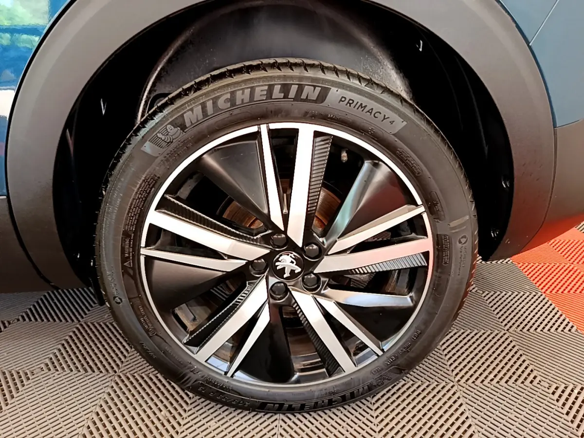 Gros plan sur la roue avant droite du Peugeot 5008 bleu, mettant en valeur la jante alliage bicolore et le pneu Michelin.