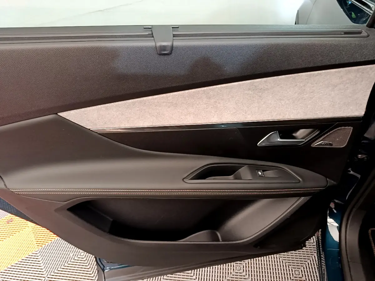 Vue intérieure de la porte arrière droite du Peugeot 5008 bleu, avec garniture tissu et cuir noir.