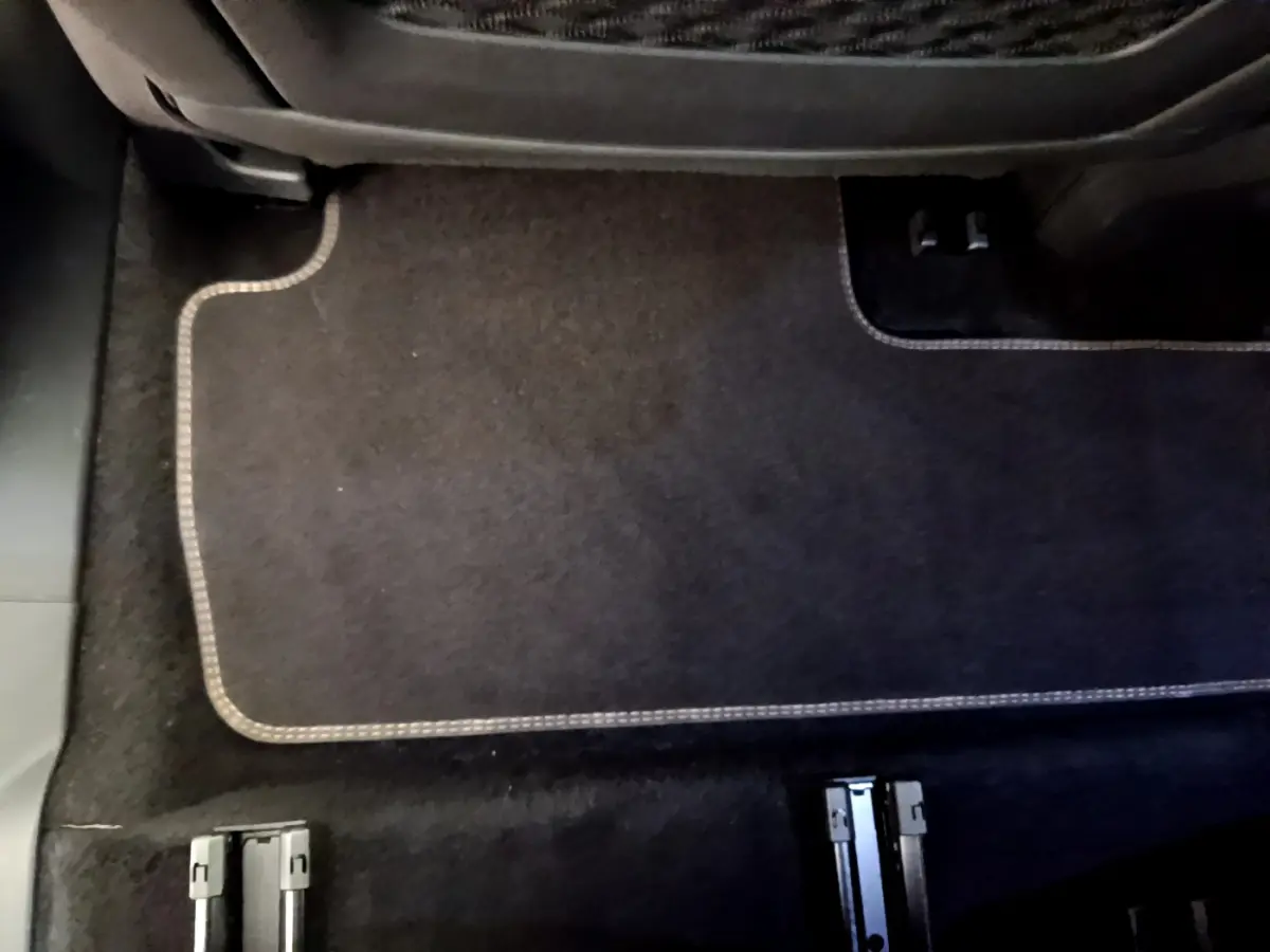 Gros plan sur le plancher arrière noir avec tapis et rails d'ancrage des sièges du Peugeot 5008 bleu.