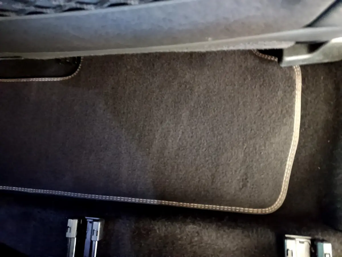 Gros plan sur le tapis de sol noir avec surpiqûres beiges dans l'habitacle du Peugeot 5008 bleu 2021.