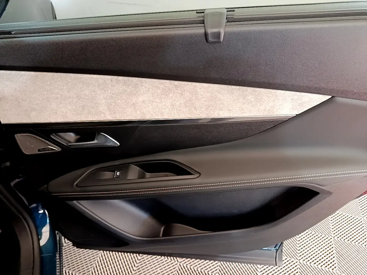 Gros plan sur la porte côté gauche du Peugeot 5008 bleu, avec garniture noire et insert tissu clair.