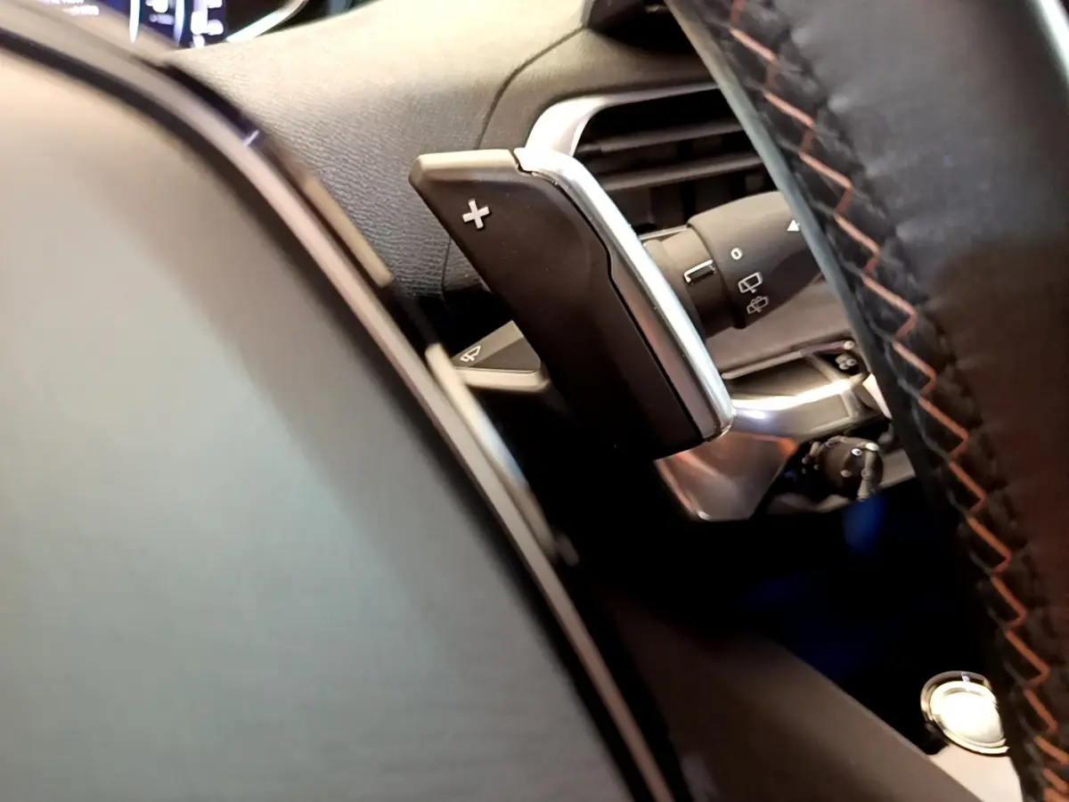 Gros plan sur la palette de changement de vitesse droite du volant cuir noir du Peugeot 5008 bleu, version GT Pack.