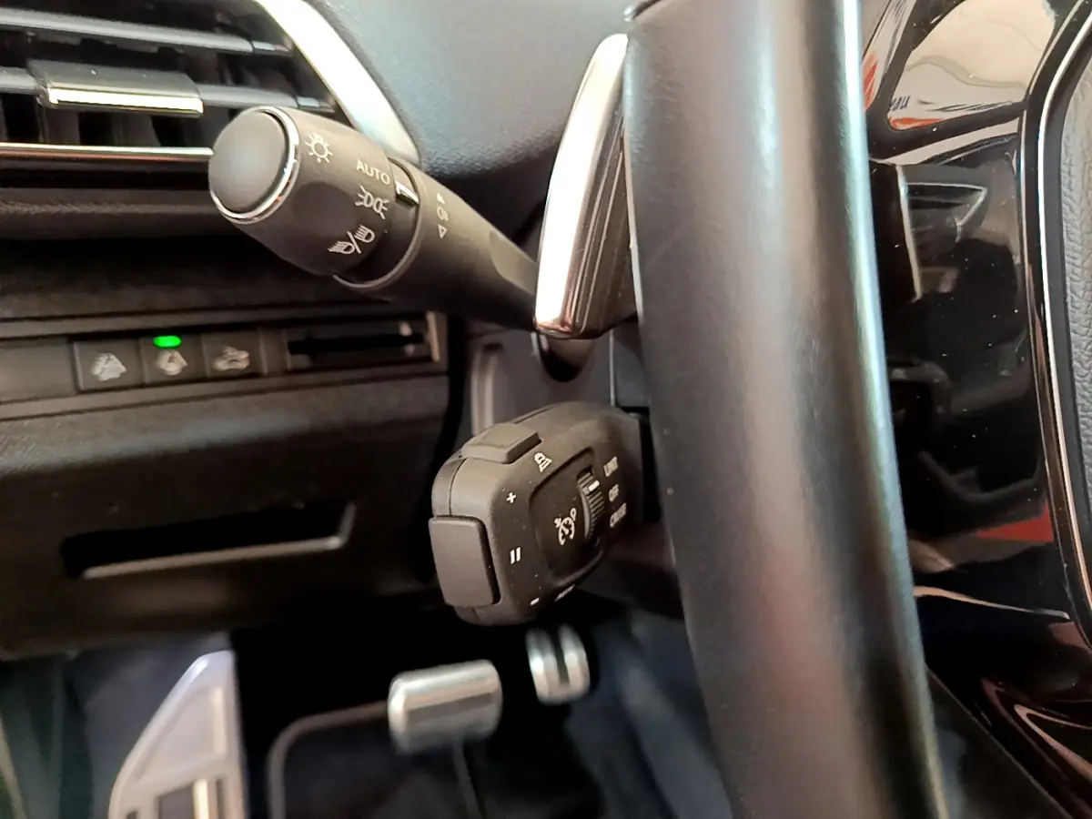 Gros plan sur la commande multifonction et levier de clignotant côté gauche du volant cuir noir du Peugeot 5008 GT Pack bleu 2021.