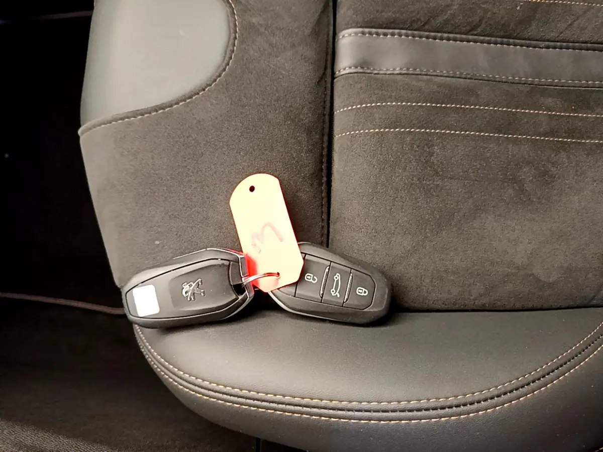 Gros plan sur la clé Peugeot posée sur un siège en cuir et alcantara noir avec surpiqûres marron du 5008 GT Pack 2021