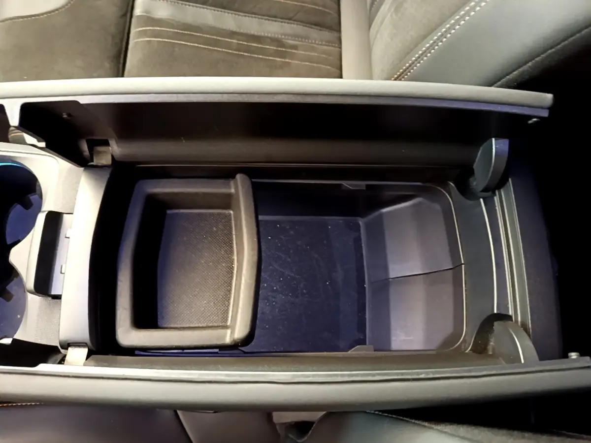 Vue plongeante sur le rangement central noir ouvert du Peugeot 5008 GT Pack 2021, sièges en tissu gris visible.