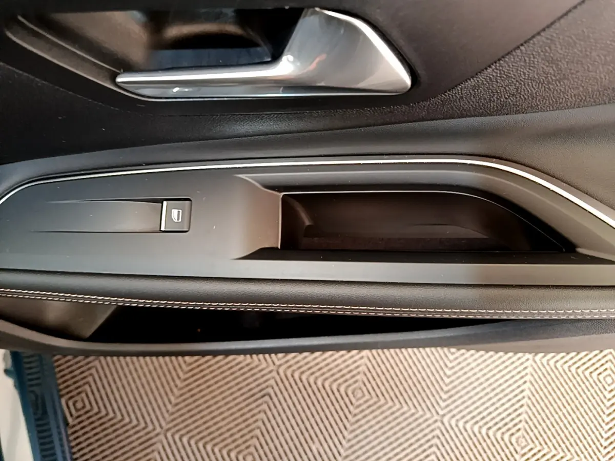 Poignée intérieure côté gauche de porte noire avec surpiqûres blanches sur Peugeot 5008 bleu 2021.