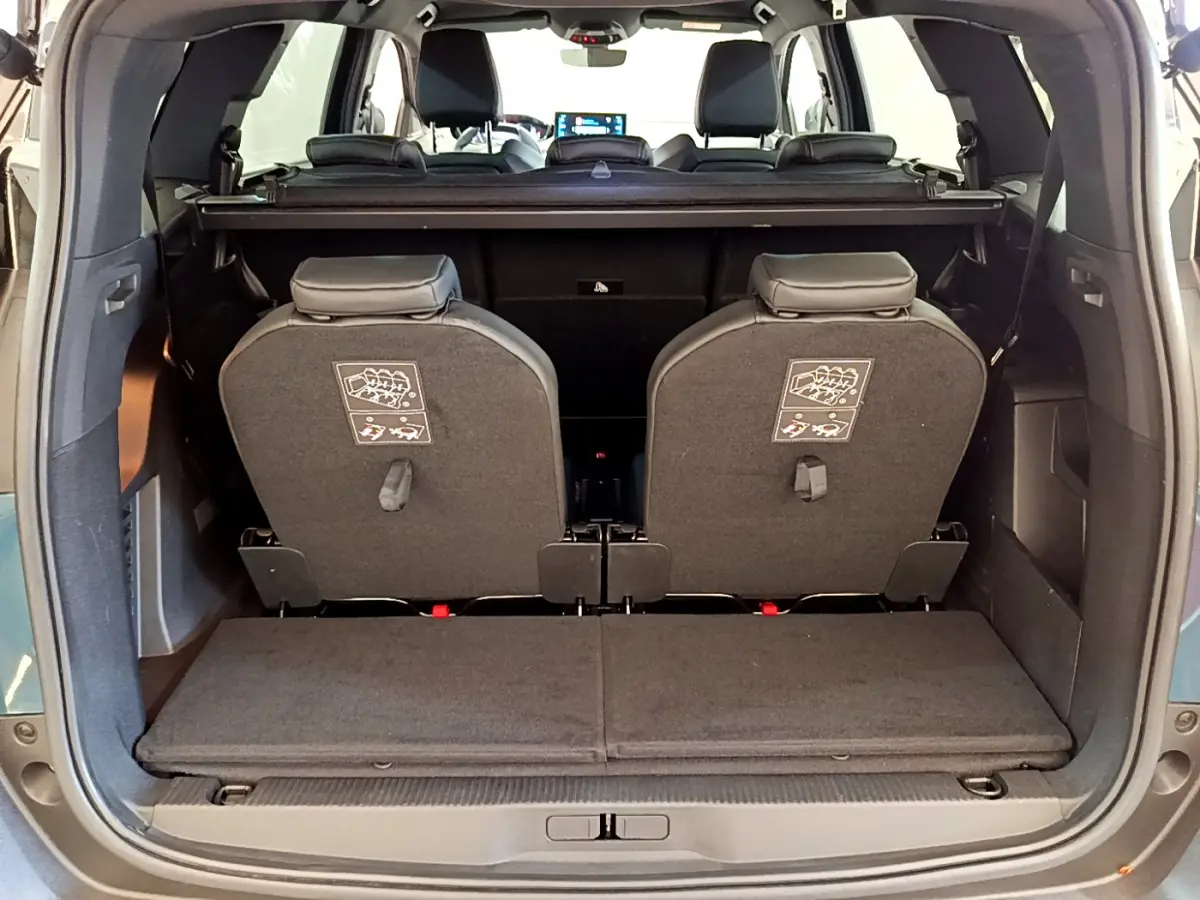 Vue arrière du coffre ouvert d'un Peugeot 5008 bleu 2021, montrant la 3ème rangée de sièges individuels rabattus.