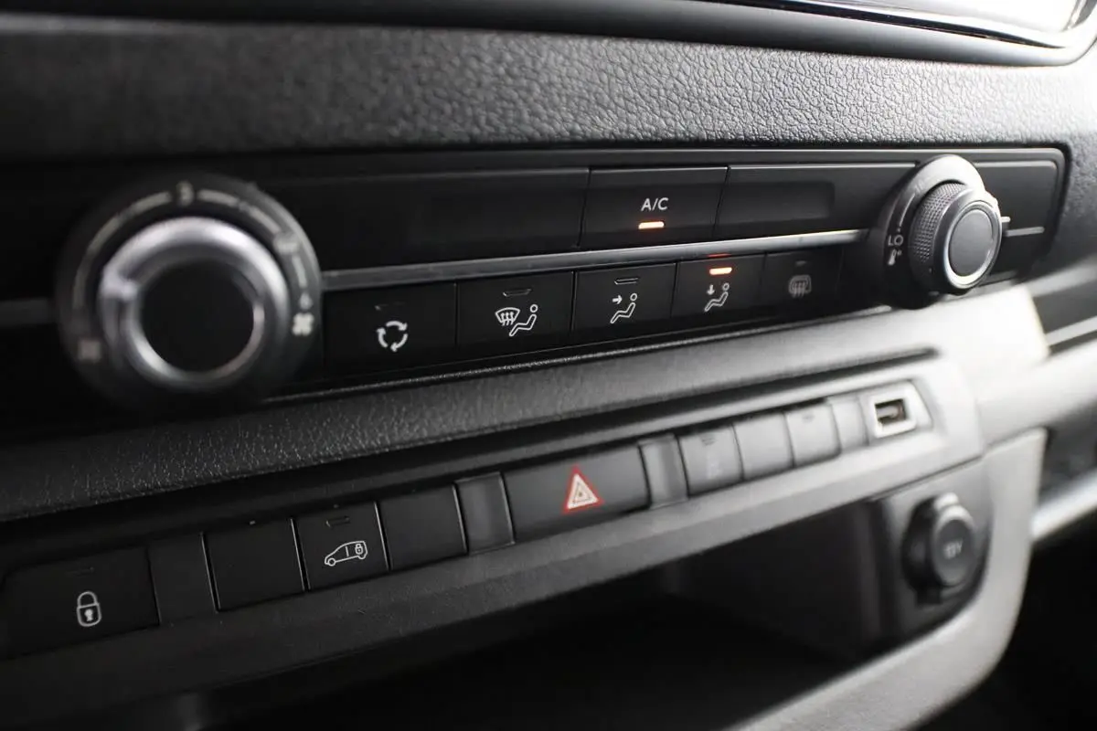 Gros plan sur la console centrale du Citroën Jumpy blanc, montrant les commandes de climatisation et les boutons de sécurité.