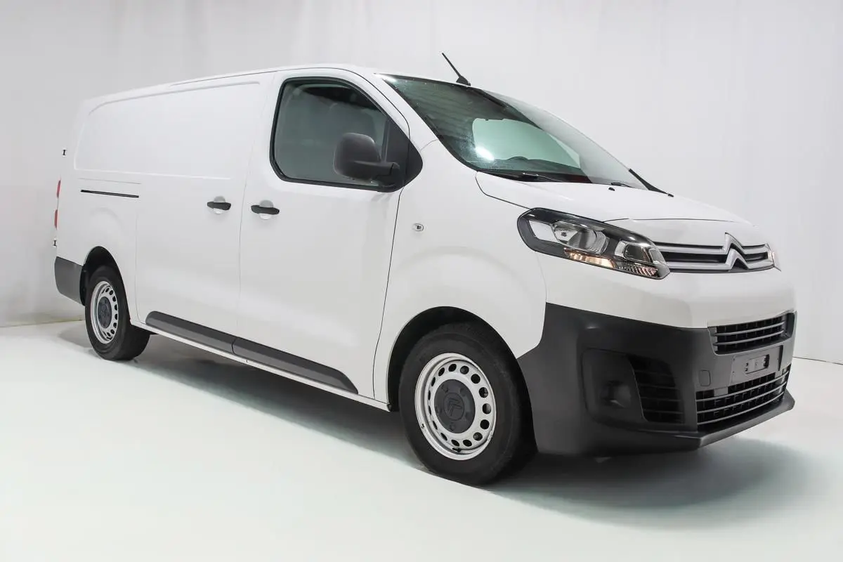 Vue 3/4 avant droite d'un Citroën Jumpy blanc version Fourgon XL avec attelage et kit bois visible.