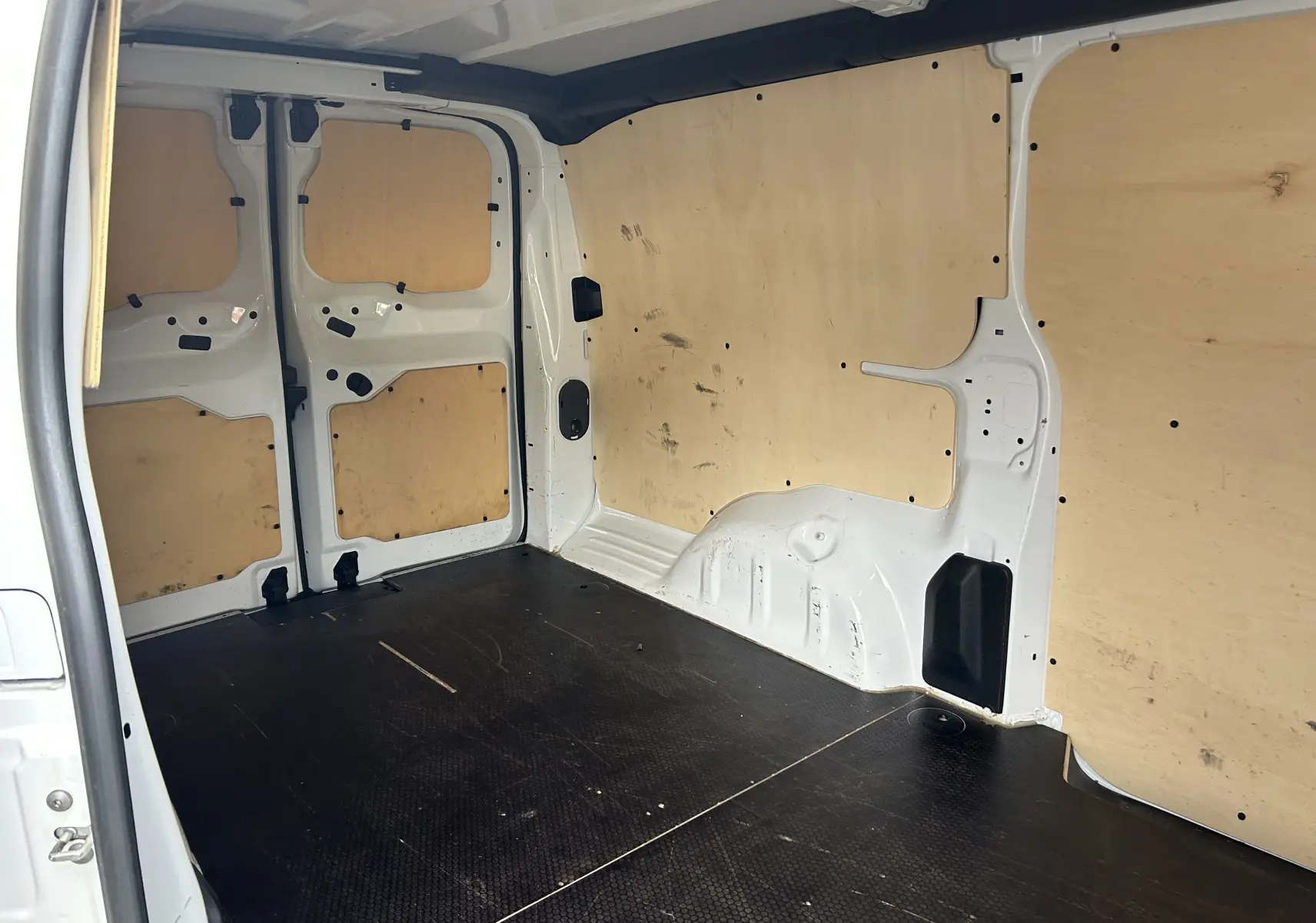 Intérieur du fourgon blanc Citroën Jumpy XL 2019, vue de l'espace de chargement avec habillage bois et sol noir antidérapant.