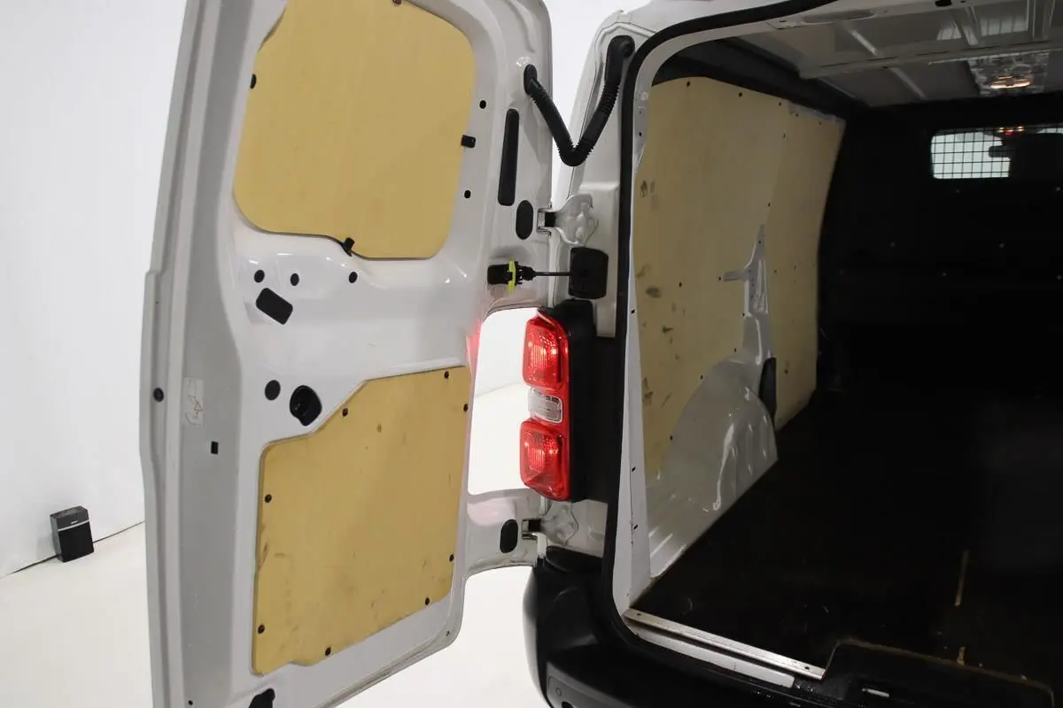 Vue arrière ouverte du Citroën Jumpy blanc, montrant l'intérieur fourgon avec habillage bois sur portes et parois.