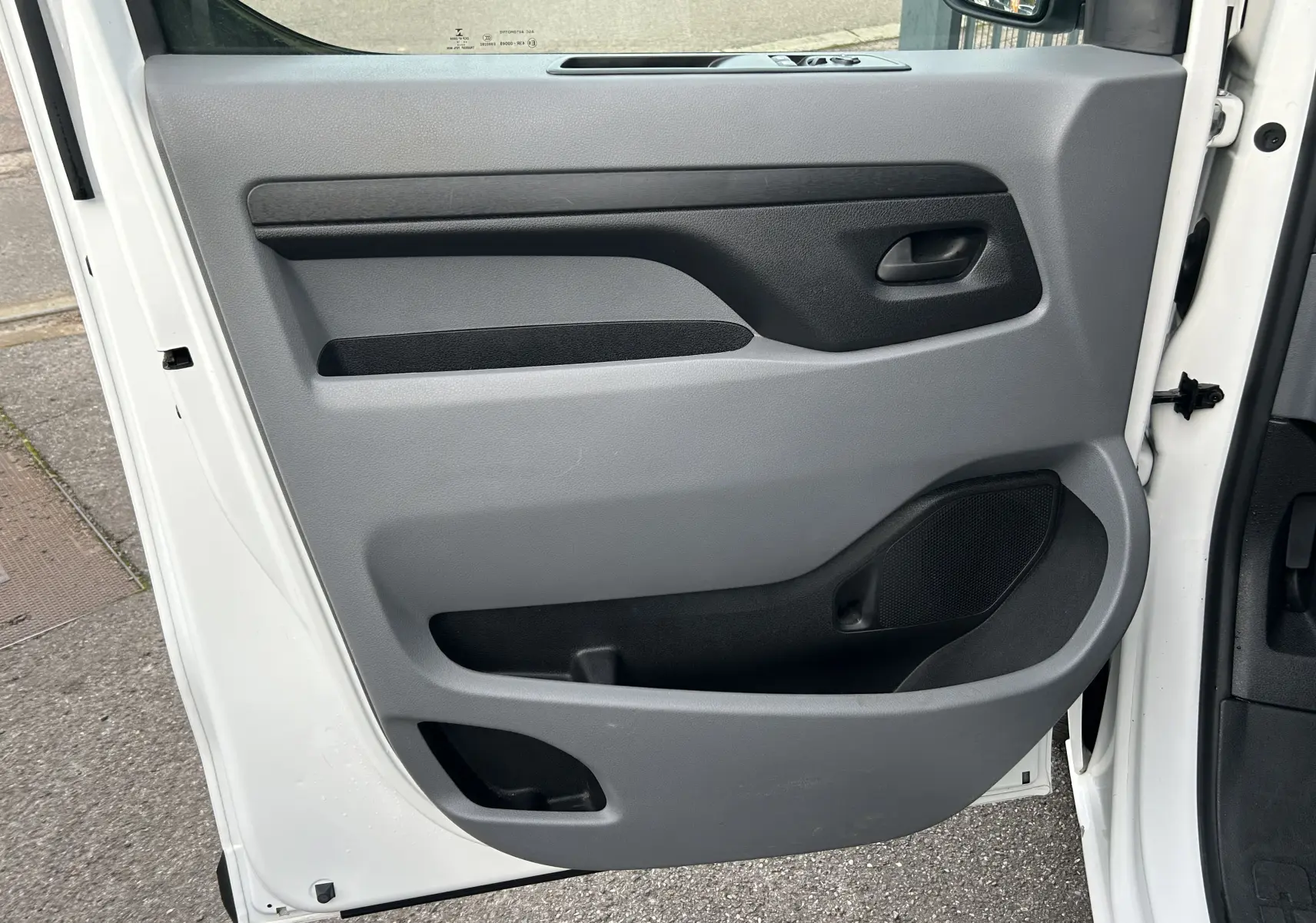 Vue intérieure de la porte avant gauche grise du Citroën Jumpy Fourgon XL blanc, avec poignée et rangement intégré.