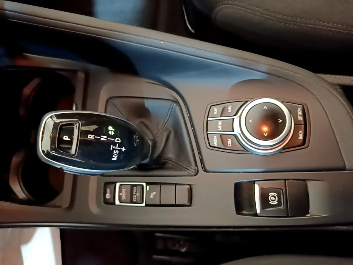 Gros plan sur la console centrale noire du BMW X1 2020 avec levier de vitesses automatique et molette de contrôle multimédia.