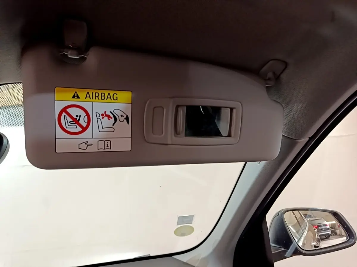 Détail du pare-soleil beige avec miroir et avertissement airbag, côté conducteur intérieur d’un BMW X1 noir 2020.