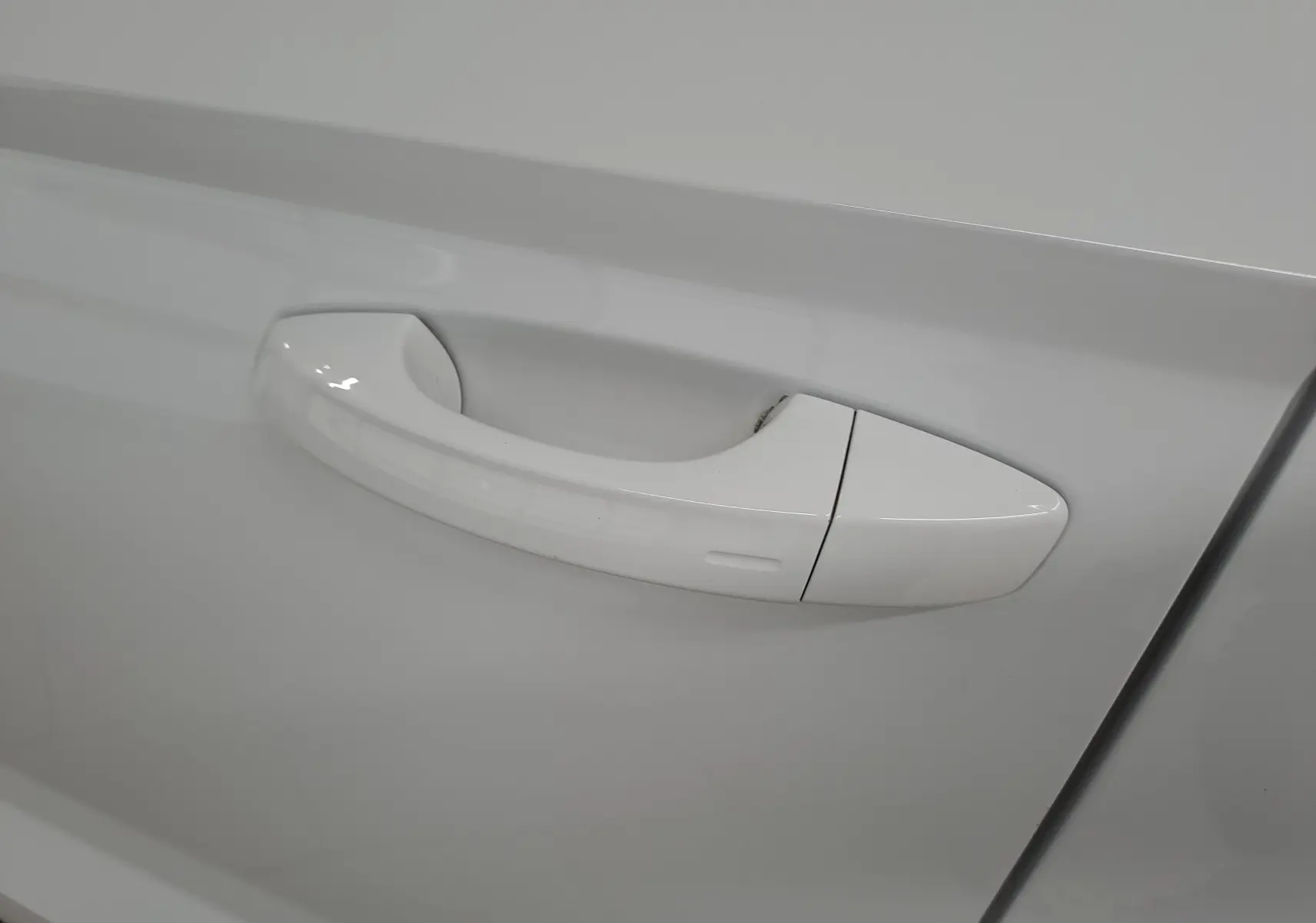 Poignée de porte blanche lune du Skoda Karoq 2025 vue en gros plan sur la portière côté droit.
