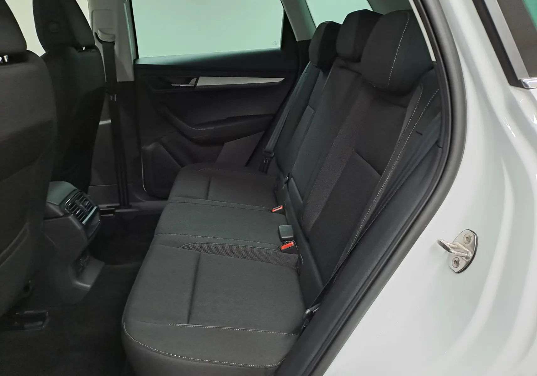 Vue intérieure côté droit sur la banquette arrière noire du Skoda Karoq blanc lune 2025, version 1.5 TSI DSG7 Selection.