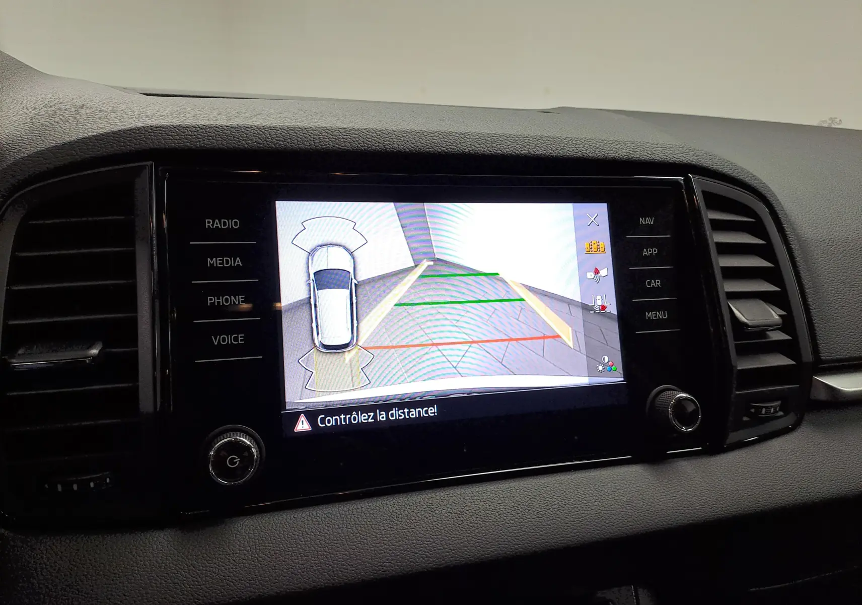 Écran central du Skoda Karoq blanc lune 2025 montrant la caméra de recul avec alertes de distance.
