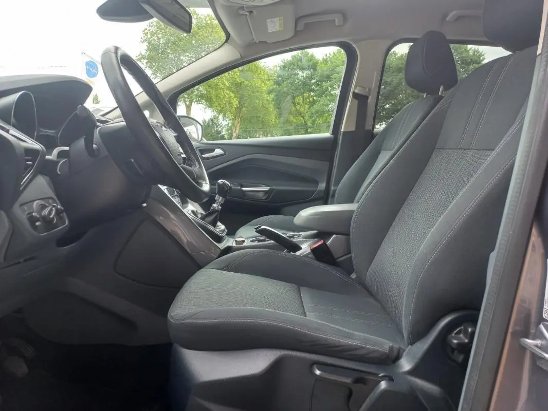 Intérieur avant droit du Ford C-MAX gris 2015, montrant sièges tissu noirs et tableau de bord avec boîte manuelle.