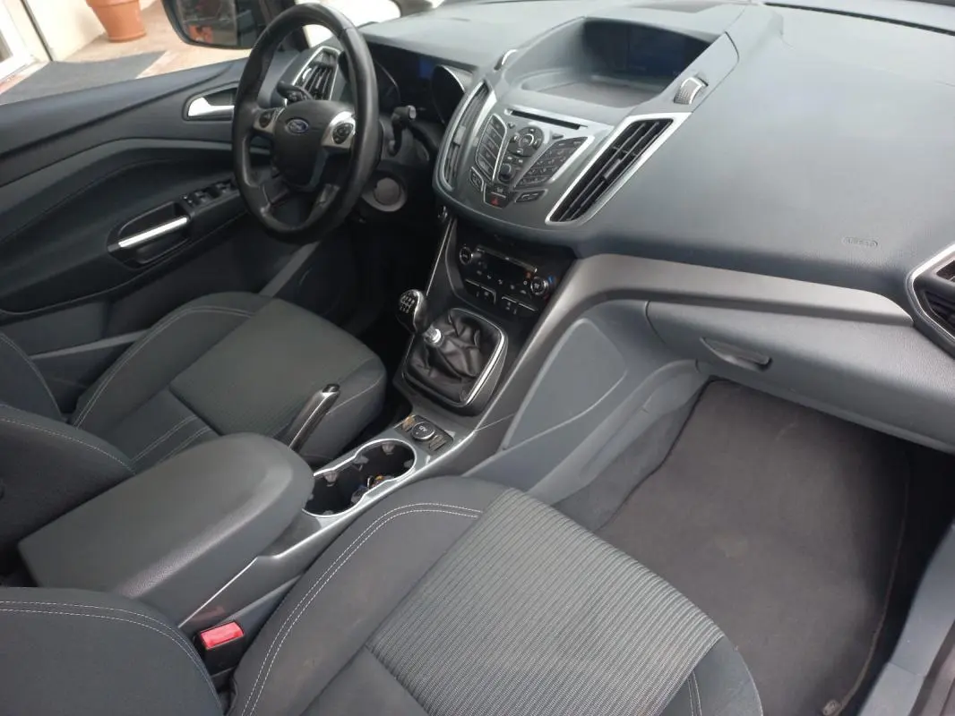 Vue intérieure côté conducteur du Ford C-MAX gris 2015, mettant en valeur le tableau de bord et la boîte manuelle.