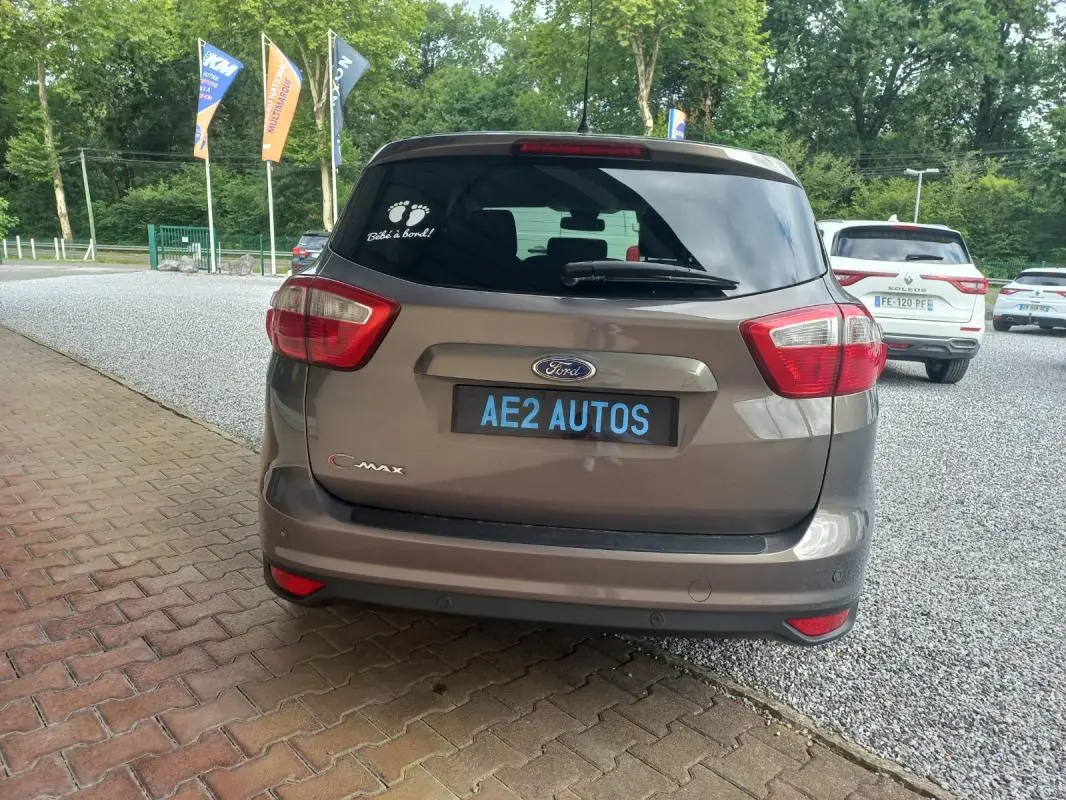Vue arrière d'une Ford C-MAX gris 2015 avec autocollant "Bébé à bord" sur la vitre arrière.