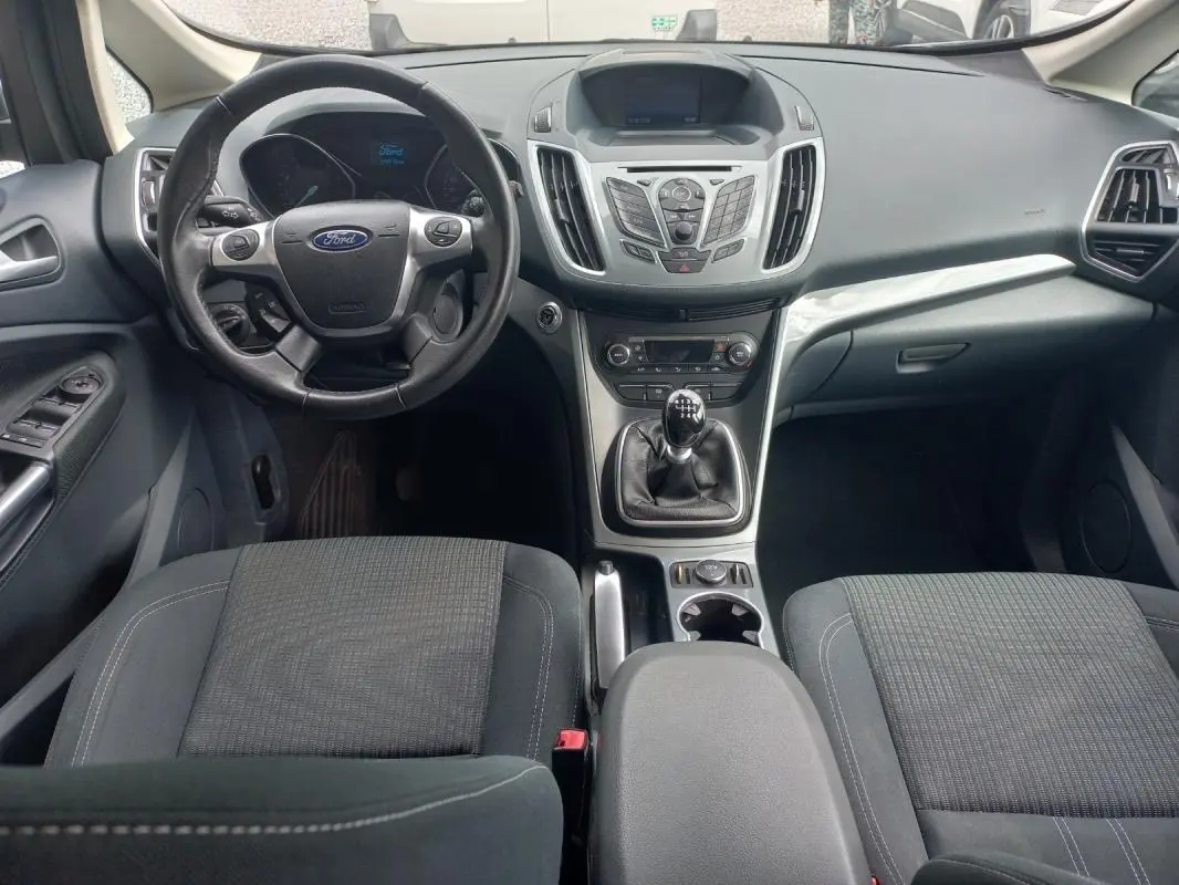Vue intérieure avant du Ford C-MAX gris 2015, avec volant, tableau de bord et levier de vitesse manuel visibles.
