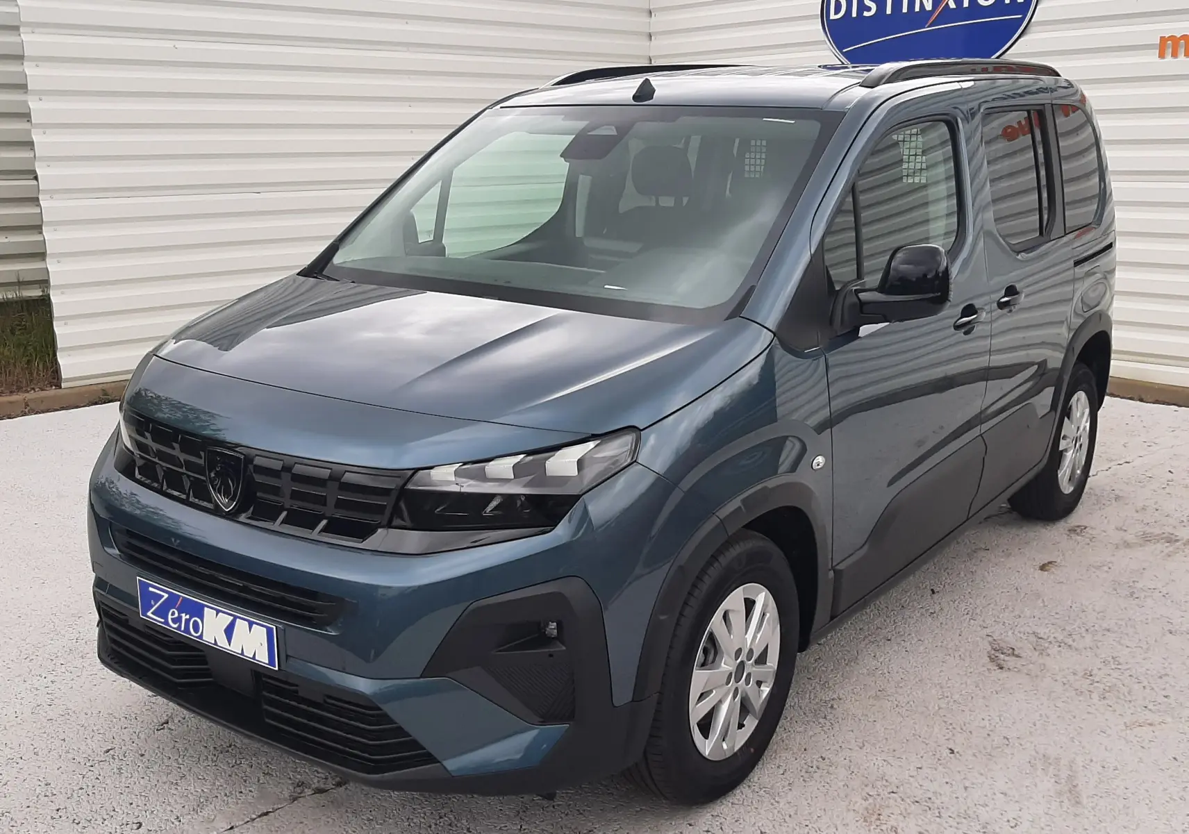 Peugeot Rifter III Ph.2 bleu Kiama en vue 3/4 avant droit, avec jantes alu 16'' et barres de toit noir mat.
