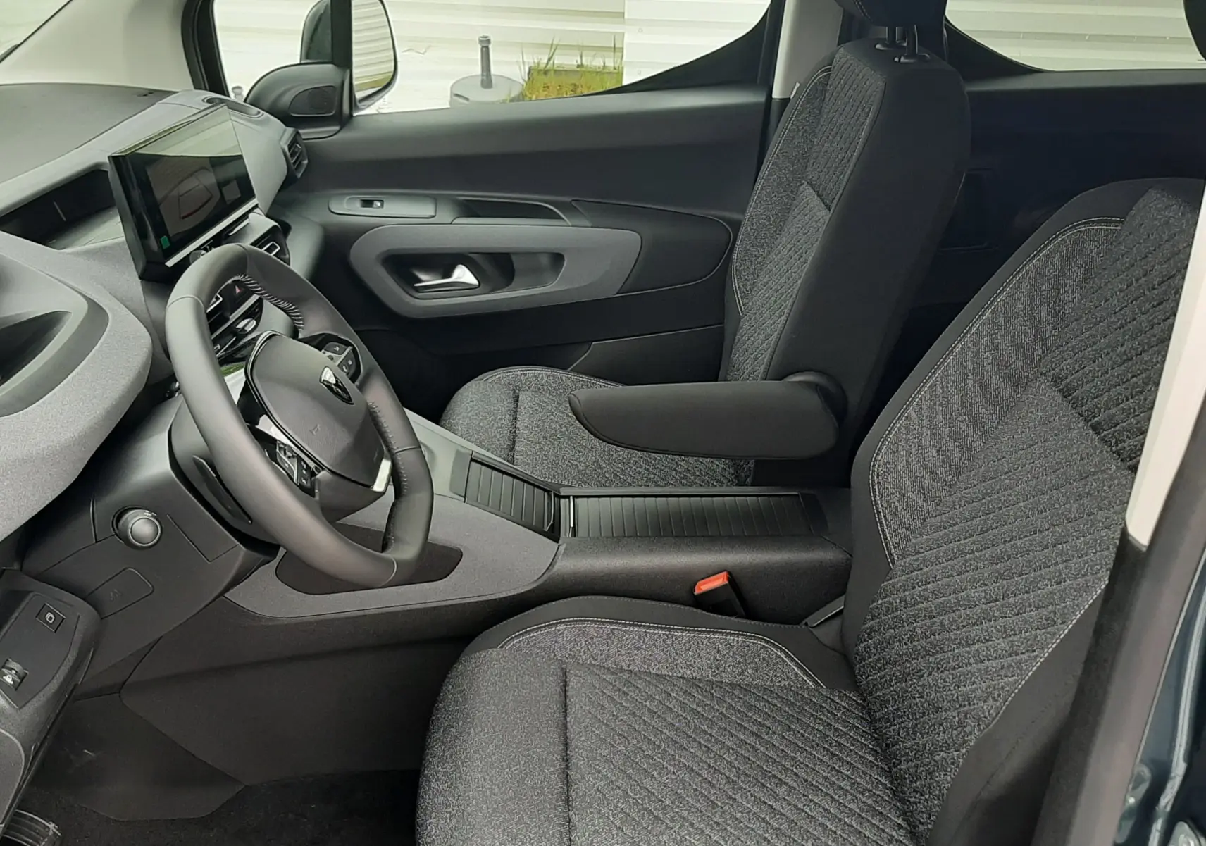 Vue intérieure côté conducteur du Peugeot Rifter Bleu Kiama 2026, avec sièges tissu gris et tableau de bord moderne.
