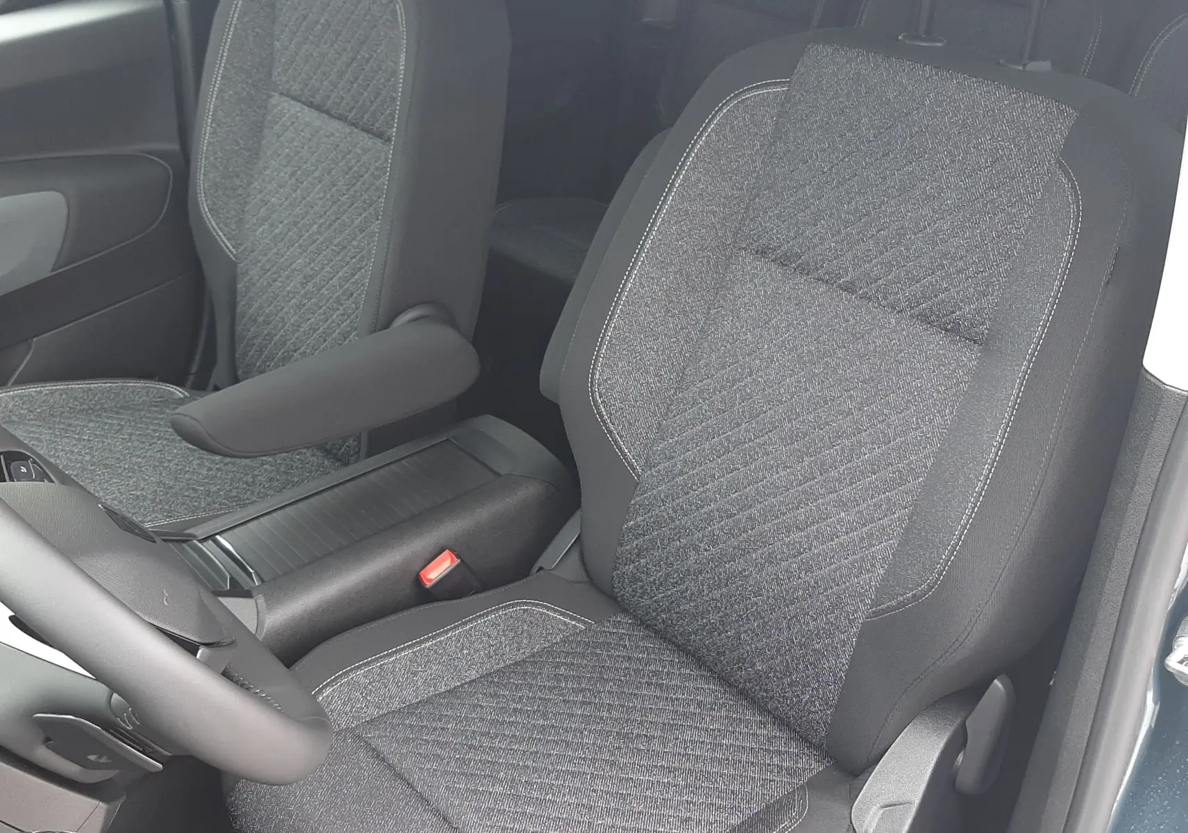 Vue intérieure côté conducteur du Peugeot Rifter bleu Kiama 2026, sièges tissu gris avec accoudoir central.