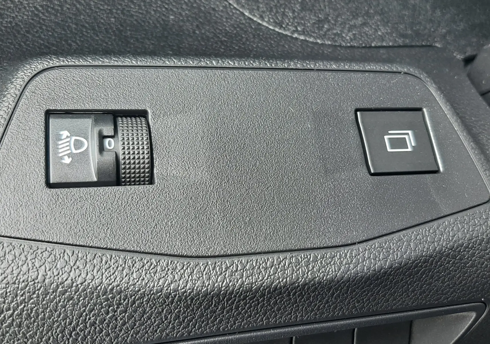 Gros plan sur les commandes de réglage des phares et bouton de fonction sur la porte intérieure du Peugeot Rifter bleu Kiama 2026.