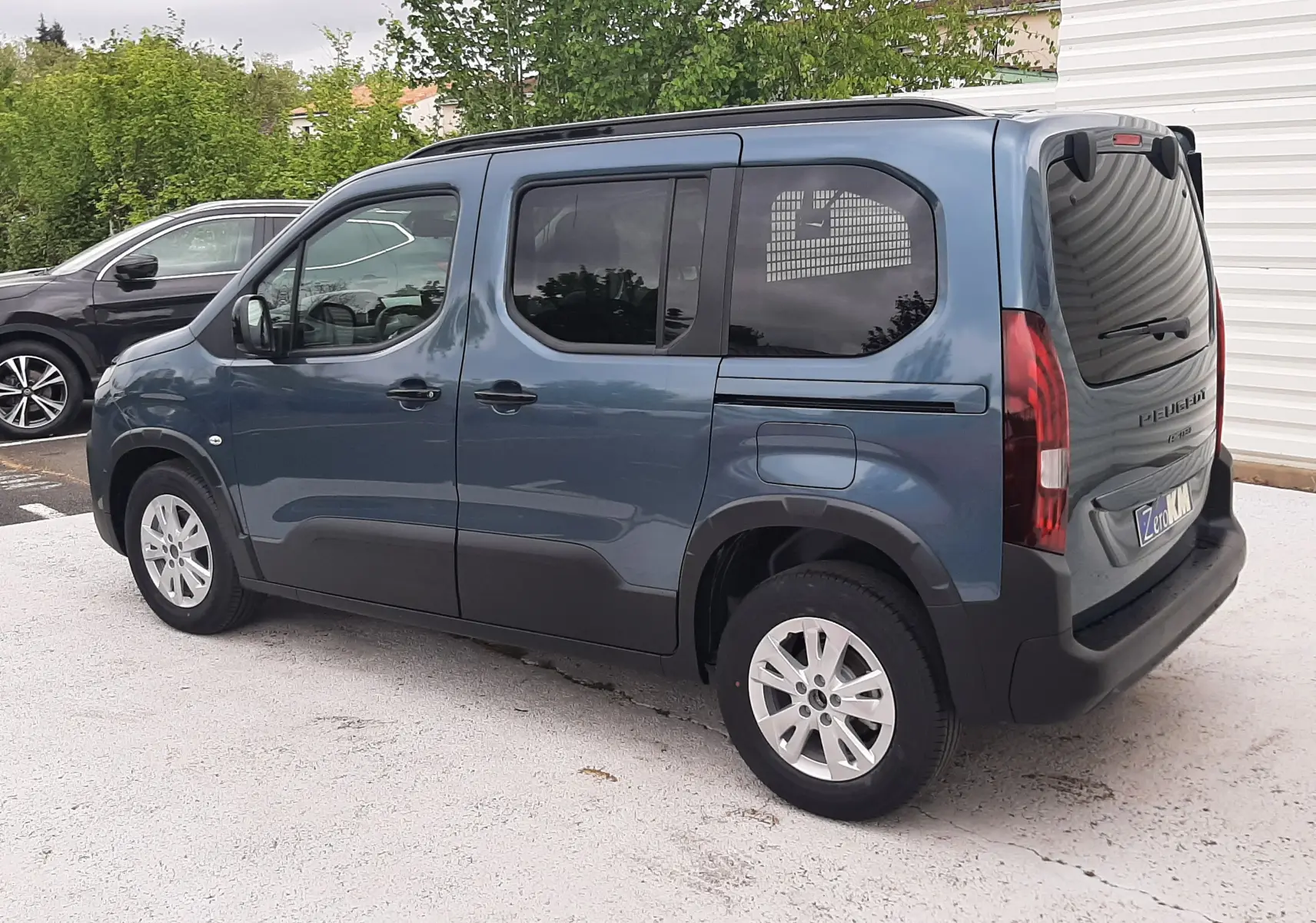 Peugeot Rifter bleu Kiama vu en 3/4 arrière côté gauche, avec vitres surteintées et jantes alu 16 pouces.