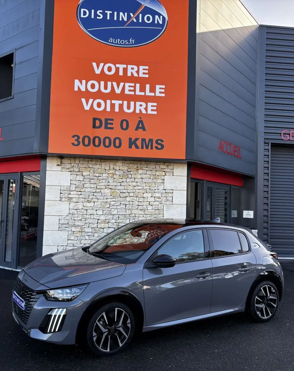 Peugeot 208 Hybrid 136 eDCS6 GT gris foncé vue 3/4 avant, avec jantes alliage et feux LED distinctifs.