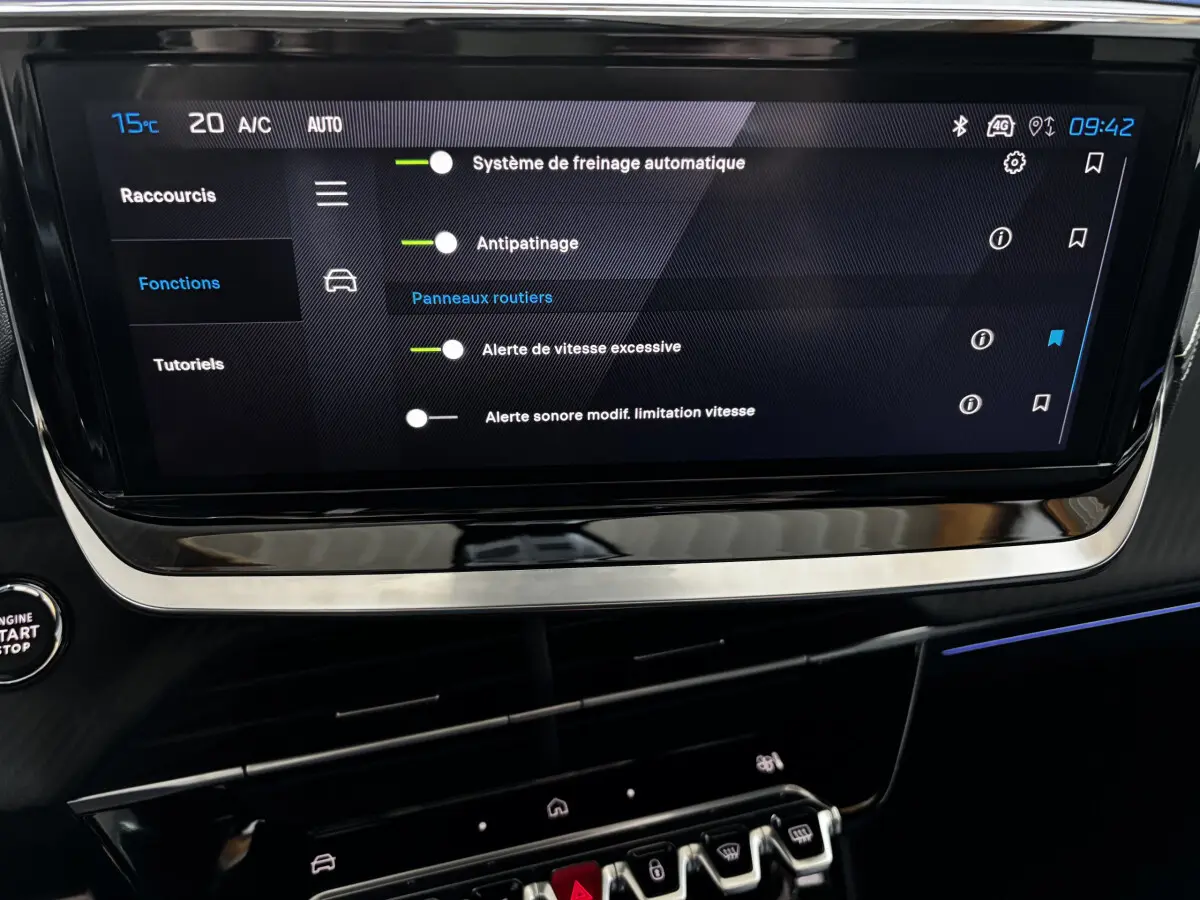 Écran tactile central affichant les réglages d'aide à la conduite dans l'habitacle sombre d'une Peugeot 208 Hybrid 136 eDCS6 GT.