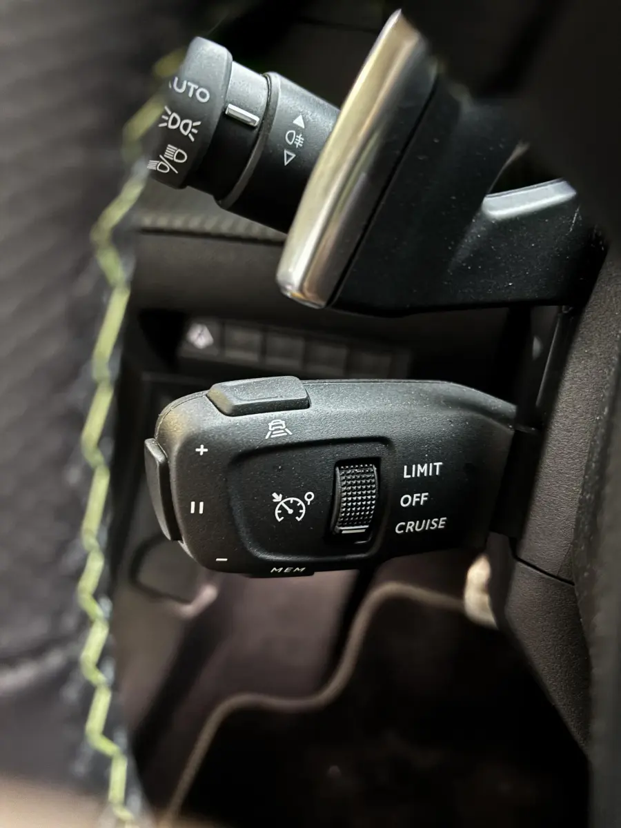 Gros plan sur la commande de régulateur de vitesse et limiteur, intérieur noir avec surpiqûres vertes du Peugeot 208 Hybrid 136 eDCS6 GT.