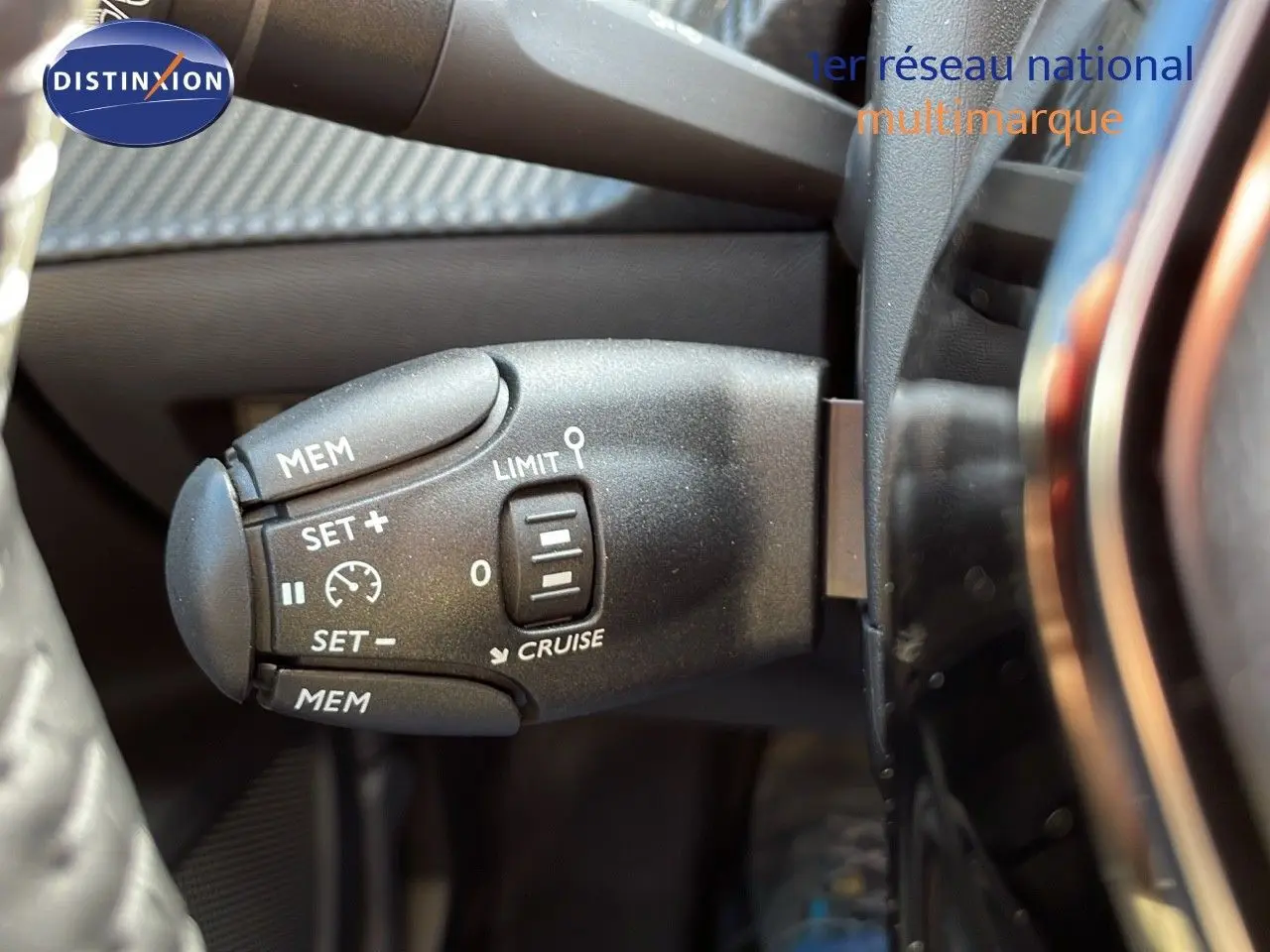 Gros plan sur la commande de régulateur de vitesse à gauche du volant d'un Peugeot 2008 bleu Vertigo Metal 2024.