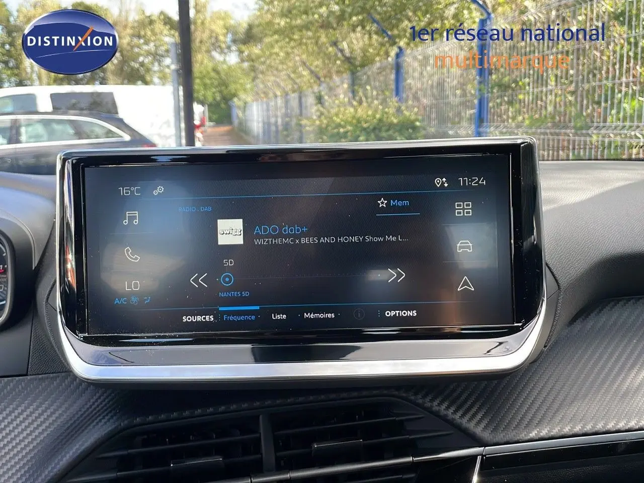 Écran tactile central du tableau de bord du Peugeot 2008 2024, affichant la radio DAB avec interface moderne et finition carbone.