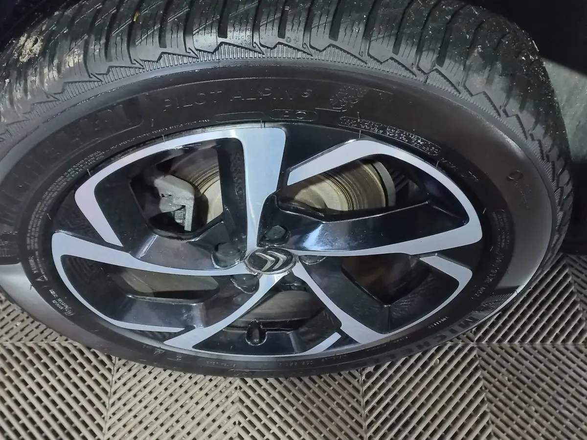 Gros plan sur la jante alliage noire et argentée avec logo Citroën d’un Citroën C5 Aircross blanc.