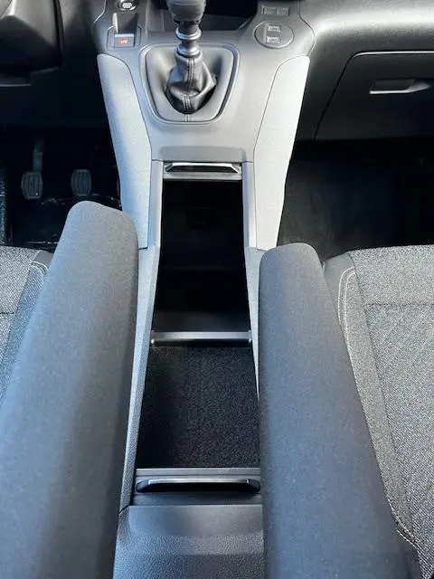 Vue plongeante sur la console centrale grise et les accoudoirs noirs du Peugeot Rifter 2024, boîte manuelle.