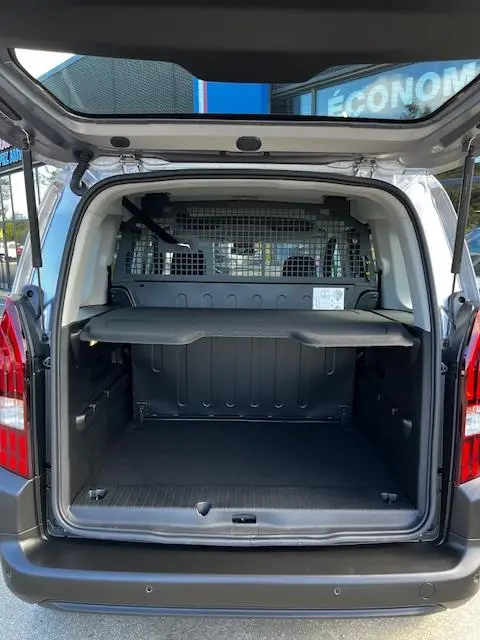 Vue arrière ouverte du Peugeot Rifter gris foncé 2024, montrant l'espace de chargement avec cloison métallique et tablette de séparation.