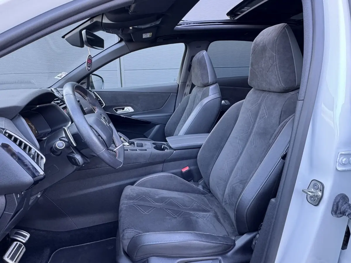 Intérieur côté conducteur du DS7 Crossback blanc, sièges en alcantara gris et volant cuir multifonctions visible.