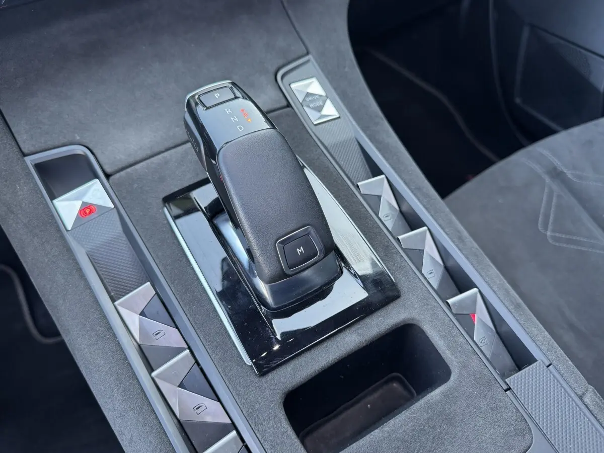 Gros plan sur la console centrale noire du DS7 Crossback avec levier de vitesse automatique et boutons triangulaires argentés.